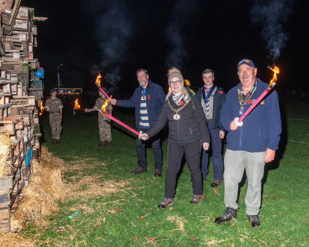 Cllr Kay with President of Rotary, Consort Mike and Cadet Barney, lighting the bonfire.