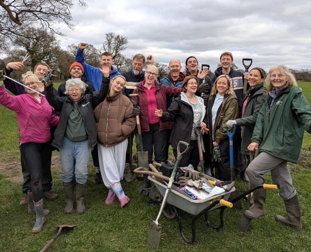Group of people from Kanga with spaces, together with Patti Pinto and Ruth Burgess, celebrating
