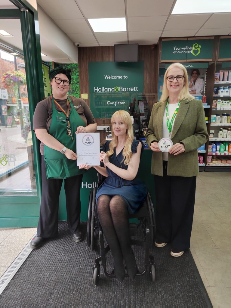 Picture shows Robin at Holland and Barratt getting the Disability Welcome Award from Dr Lawson in the shop, with Kay looking on.