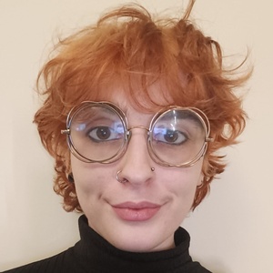 Image of Caitlin showing a young woman with short ginger hair and round glasses. 