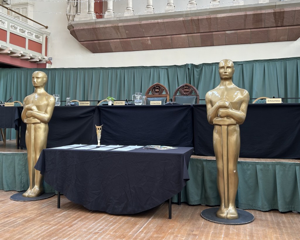 Two 'oscar' statues and a table of awards.