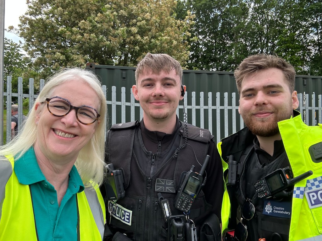Kay - blond woman, with two male police officers in hi-vis jackets.